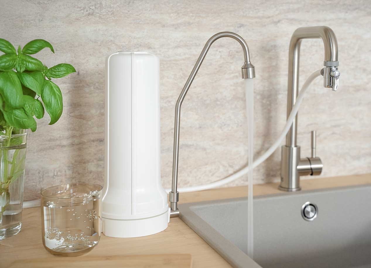 Auftisch Wasserfilter Ein Auftisch Wasserfilter steht angeschlossen in einer hellen Küche