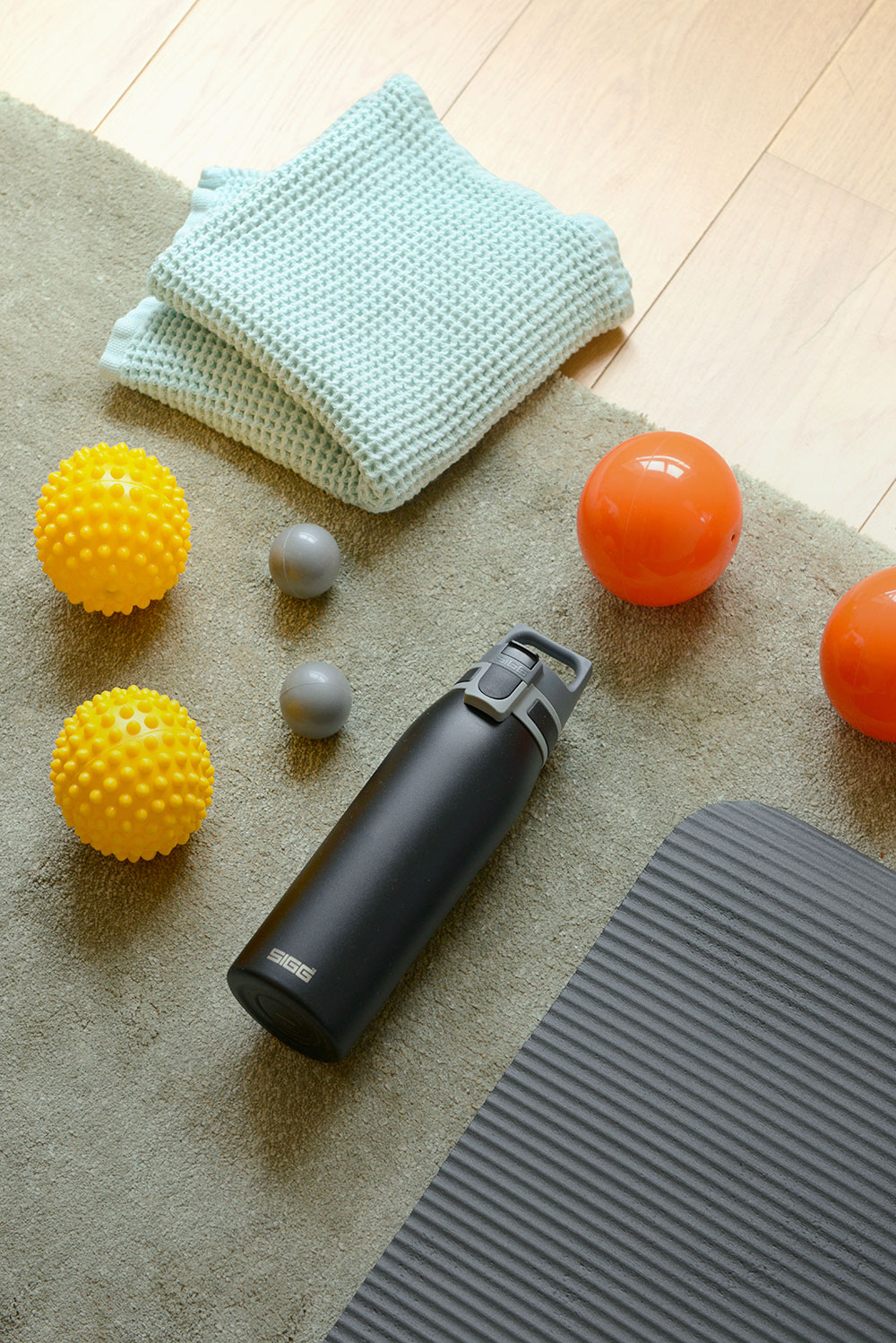 Trinkflasche auf einer Sportmatte mit Handtuch und Massagbällen