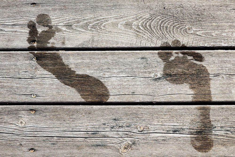 Wasserfußabdruck Zwei Wasserfußabdrücke auf einem Holzboden