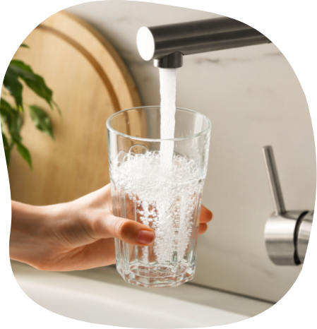 Gefiltertes Wasser aus dem Wasserhahn Hand hält ein Glas unter einen Wasserhahn, aus dem Wasser fließt